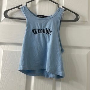 Blue cropped halter tank reads “trouble”